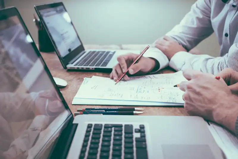 Two people with laptops and documents having an advice-only financial planning meeting